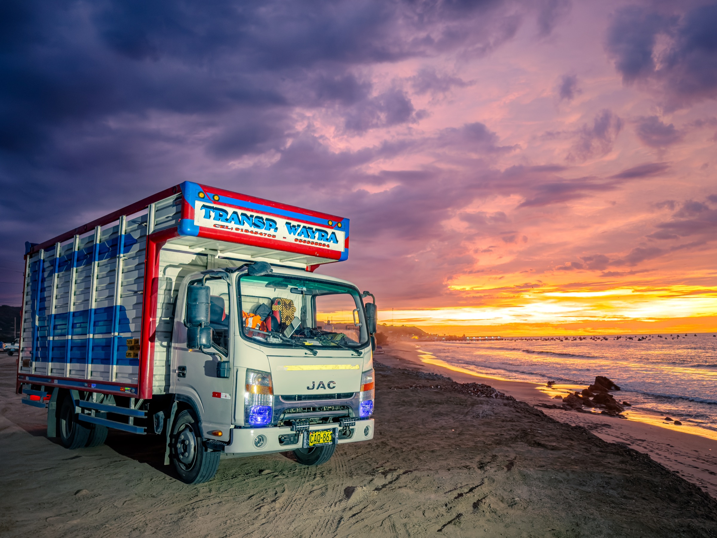 Camión de WAYRA TLI detenido frente al mar durante un atardecer en la costa peruana