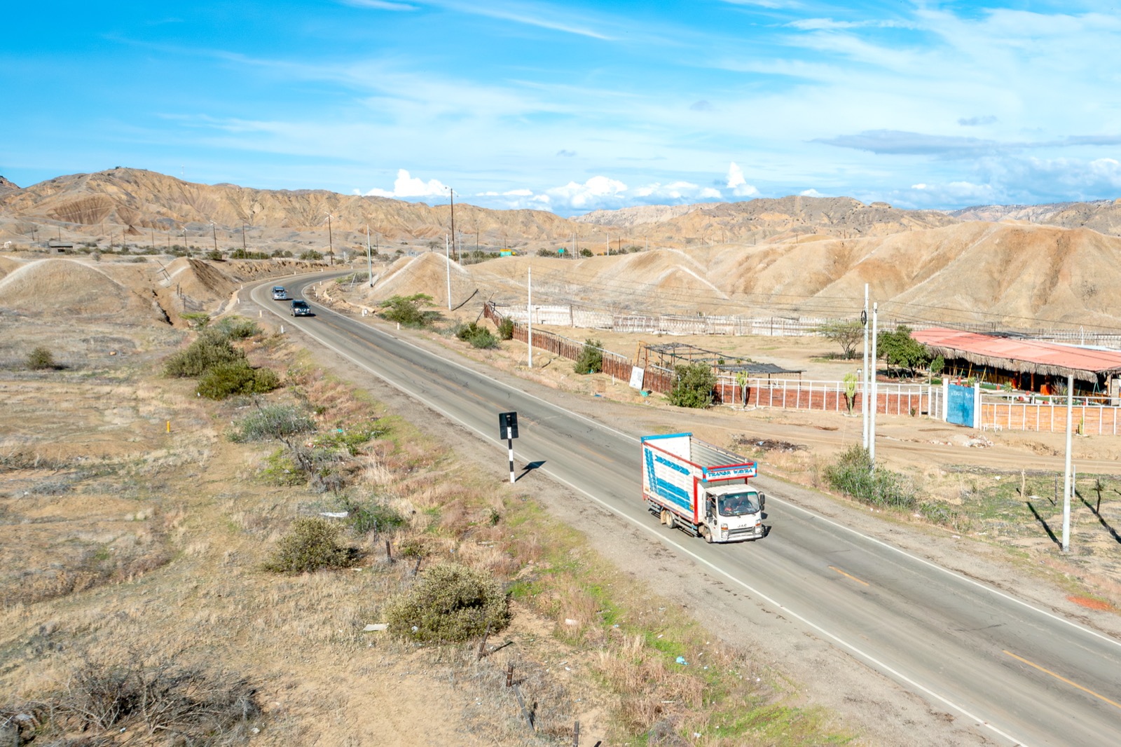 Vista aérea de un camión WAYRA circulando por una carretera del desierto costero peruano
