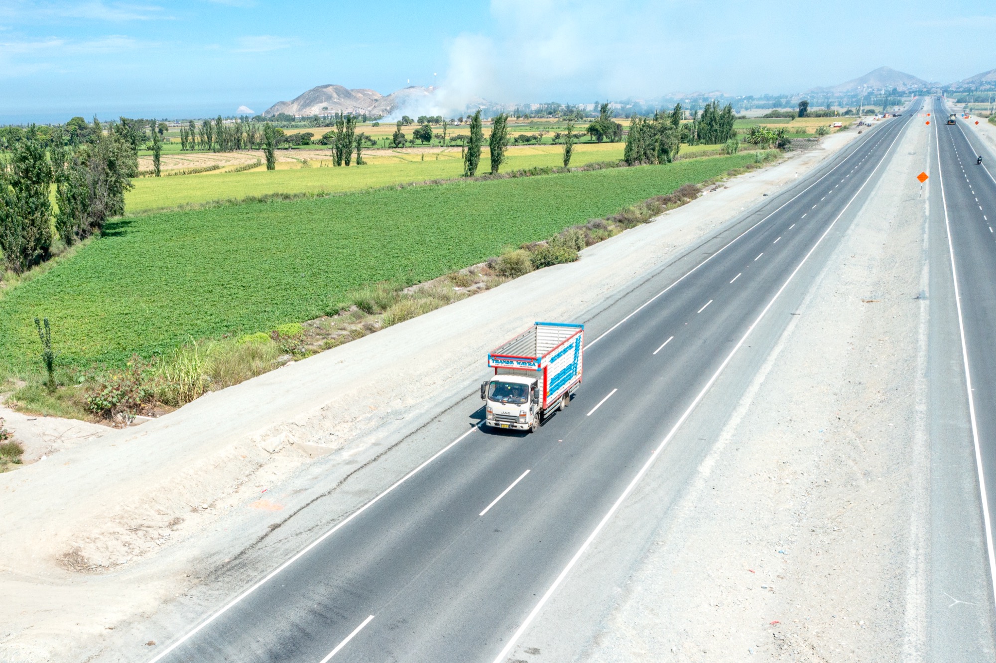 Camión WAYRA circulando por la Panamericana junto a campos de cultivo en la costa peruana